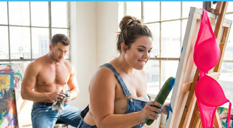 A woman in an art studio painting on a canvas using a corn on the cob instead of a brush, revealing a funny logical error.